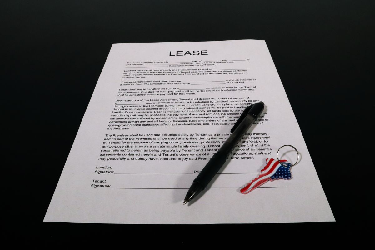 Lease agreement document with pen and American flag keychain on a black table.